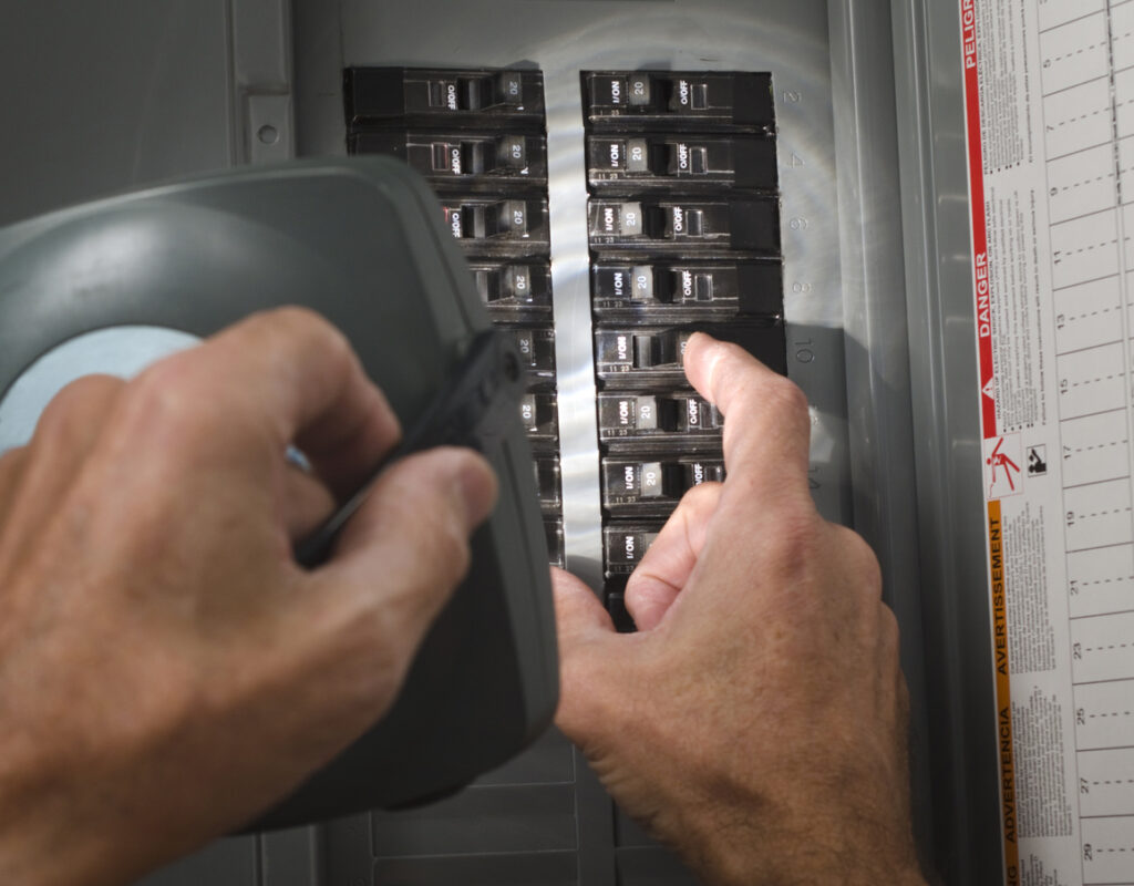 Man inspecting an electrical panel/circuit breaker with a flashlight