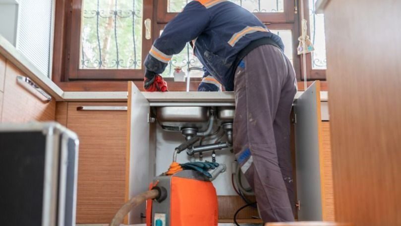 Plumber unclogging kitchen sink drain.