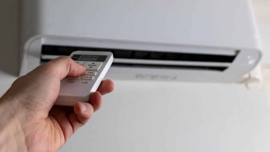 Homeowner changing the settings on a mini-split that helps regulate rooms with energy efficiency