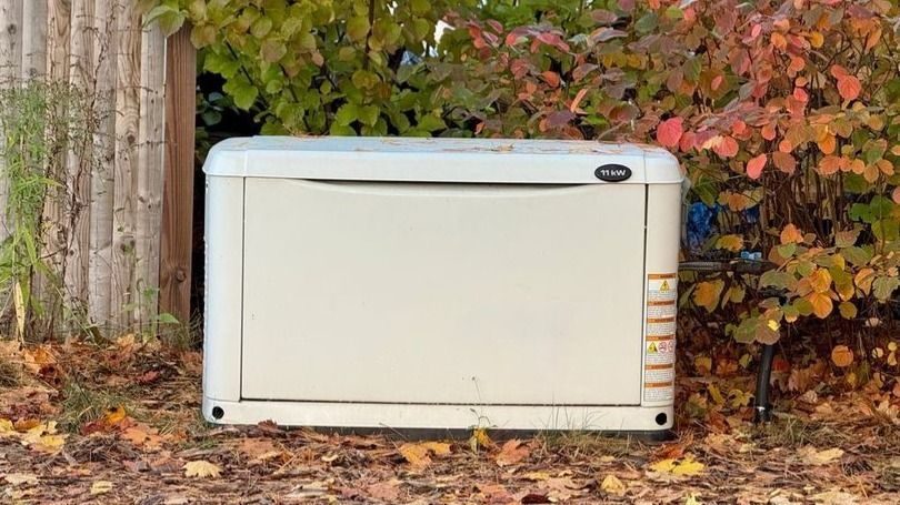 Generator near a fence and bush that needs repairs.