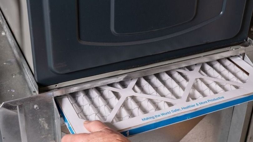 Person removing a pleated air filter from a metal housing of an industrial machine...