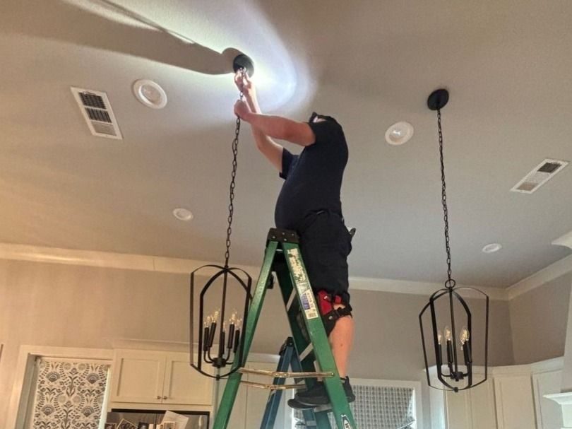 Stuart technician installing a chandelier in a kitchen.