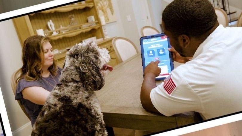 Professional technician going through the installation process with a client and dog at the table.