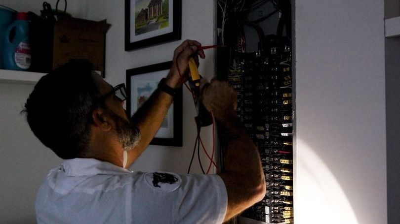 Electrician testing an electrical circuit panel for repairs needed.