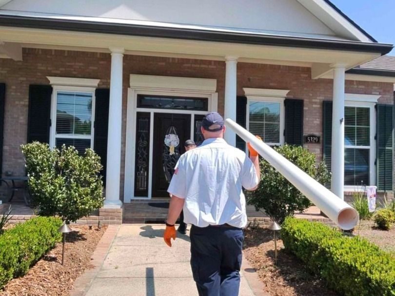 Professional plumber bringing inside piping materials for a repiping service at a home.