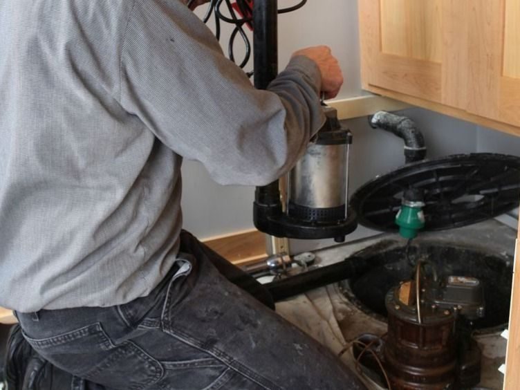 Professional Plumber installing a sump pump in a home.