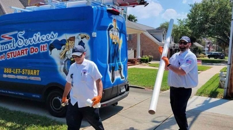 Plumbers near their company van, pulling out piping for new line for home.