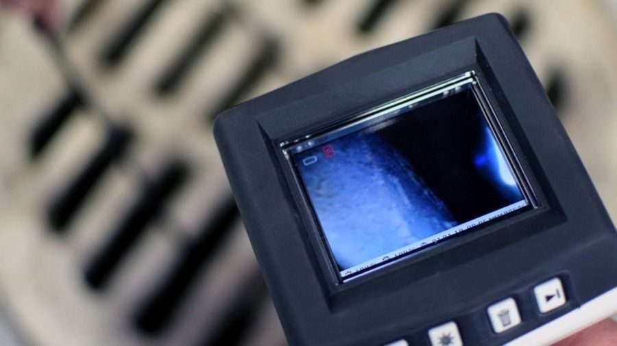 Close-up of a handheld device with a small color LCD screen showing a blue image.