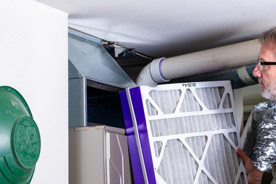 HVAC technician replacing furnace filter as part of routine HVAC maintenance